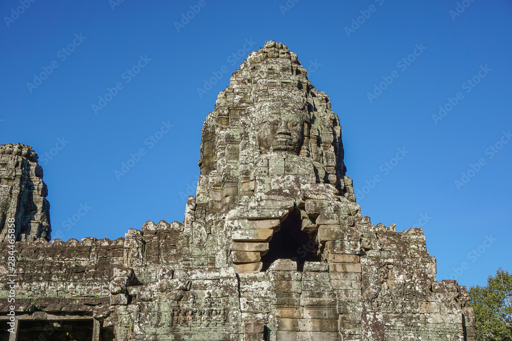 Detail Mural faces in the stone of Bayon belong angkor thom nearly angkor wat is popularity of the site among tourists with blue sky in background. UNESCO World Heritage Site. Siem Reap, Cambodia