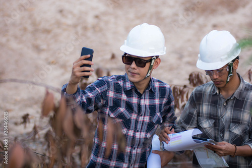 portrait of two engineer's or architect's dress with hardhat, safety helmet have a taking selfie white cell phone photo