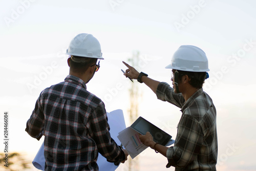 portrait of two engineer's or architect's dress with hardhat, safety helmet meeting outdoors at sunrise or sunset photo