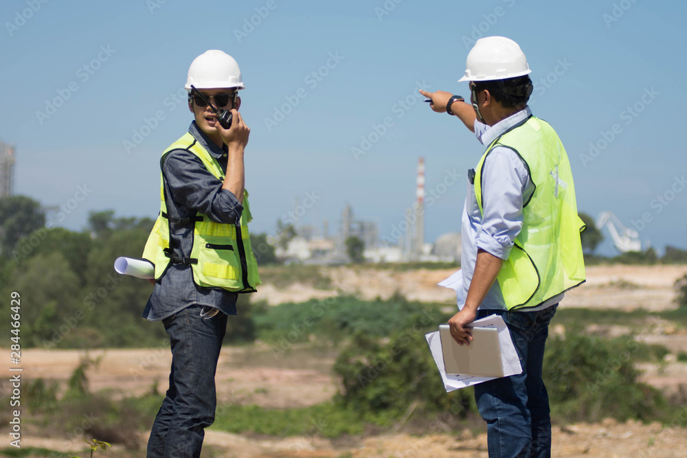 portrait of two engineer's or architect's dress with hardhat safety helmet and safety vest have a meeting and pointing to new construction sites at outdoor portrait of two engineer's or architect's dress with hardhat safety helmet and safety vest have a meeting and pointing to new construction sites at outdoor