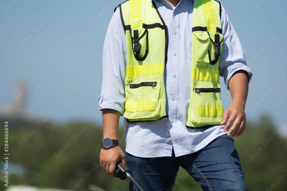 close up bottom front view of male engineer touch his black eyeglasses looking on bright blue sky for planing a construction dress with protective vest close up bottom front view of male engineer touch his black eyeglasses looking on bright blue sky for planing a construction dress with protective vest
