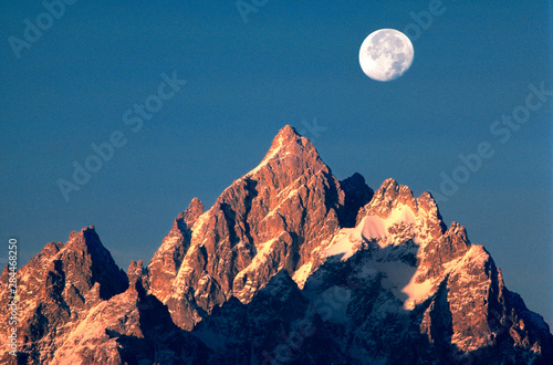 USA  Wyoming  Grand Teton NP. A full moon sets behind the Grand Teton peaks in Grand Teton NP  Wyoming.