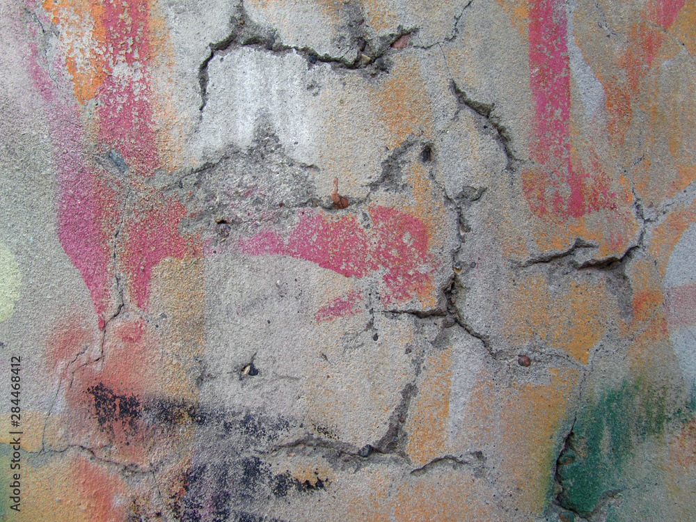   The concrete wall is collapsing. Cracks in the wall. Spots of colored paint on an old wall.     