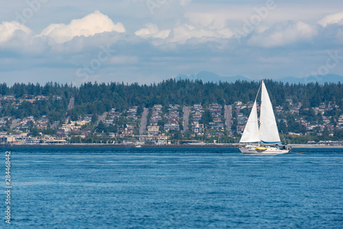 USA, Washington State. Sailboat passes Edmonds, Puget Sound