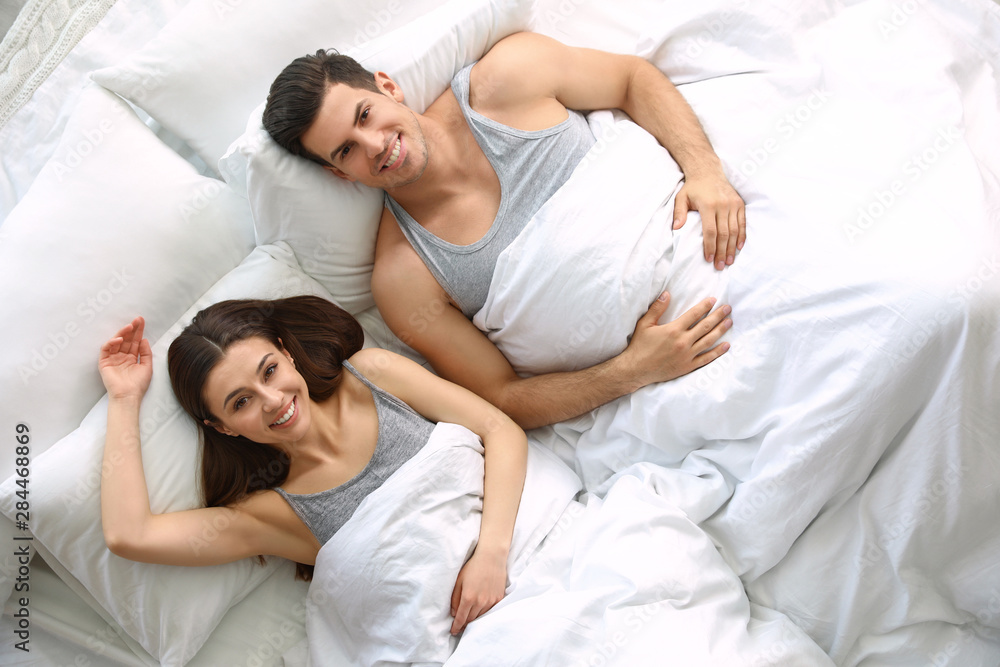 Lovely young couple resting in large bed, above view