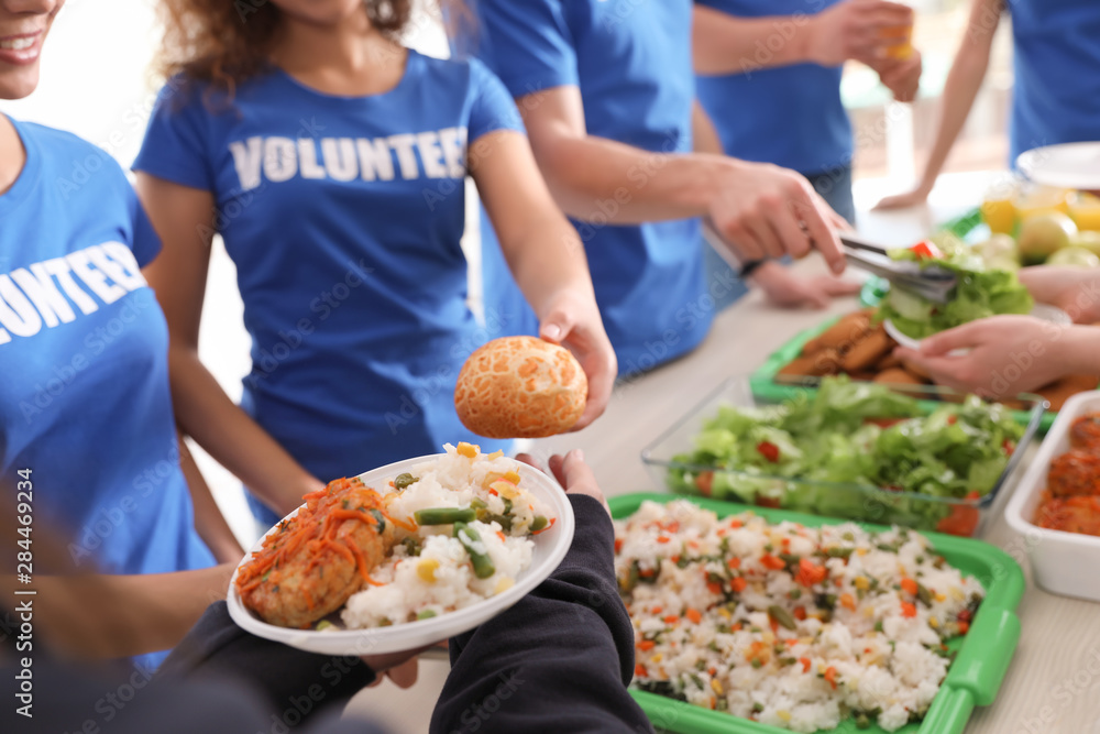 Volunteers serving food to poor people, closeup Volunteers serving food to poor people, closeup