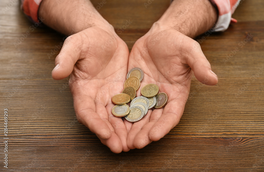 Senior man holding coins in hands at table, closeup Senior man holding coins in hands at table, closeup