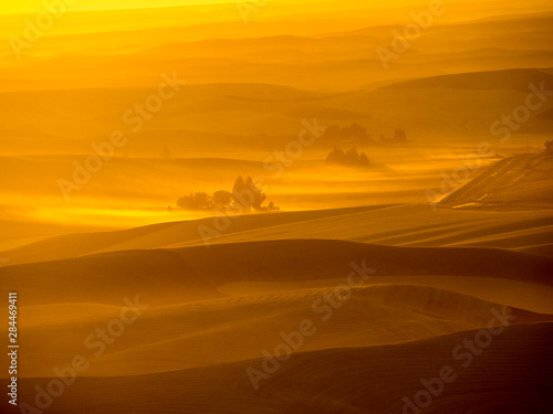 Sunset over rolling hills with dust in the air