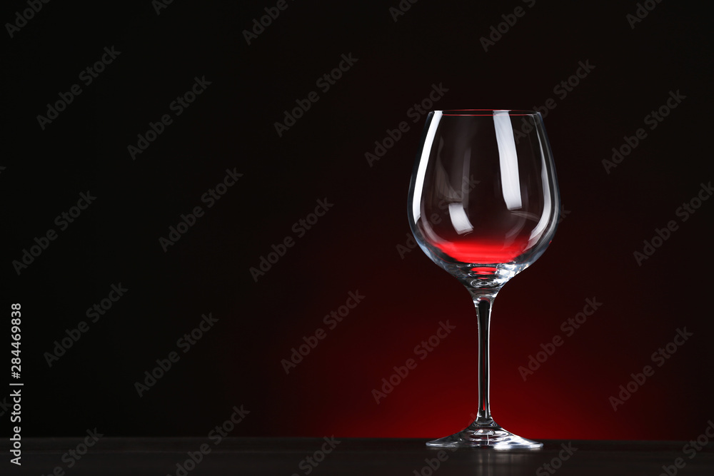 Empty wine glass on table against dark background, space for text