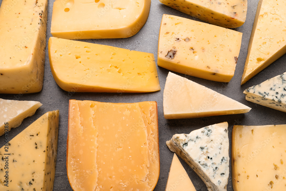Different kinds of delicious cheese on stone background, top view