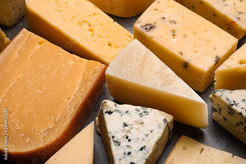 Different kinds of delicious cheese on stone background, closeup