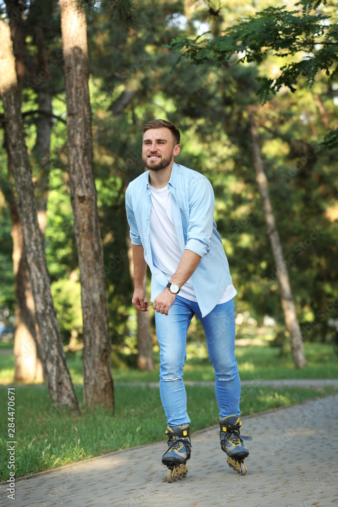Young man roller skating in summer park