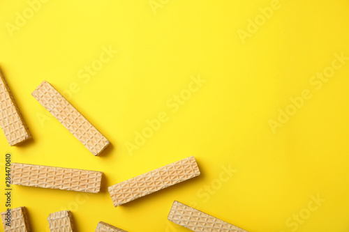 Flat lay composition with delicious crispy wafers on yellow background. Space for text