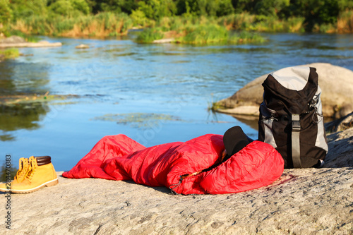 Woman resting in sleeping bag near lake on sunny day