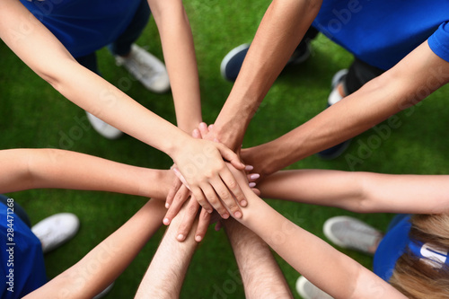 Tableau sur toile Group of volunteers joining hands together outdoors, top view