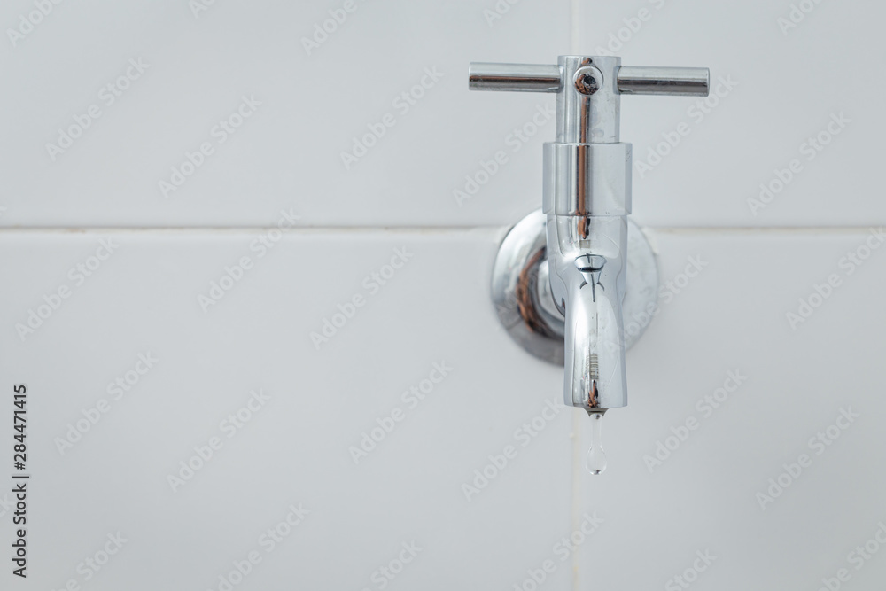 Silver metal faucet on white tile floor Silver metal faucet on white tile floor