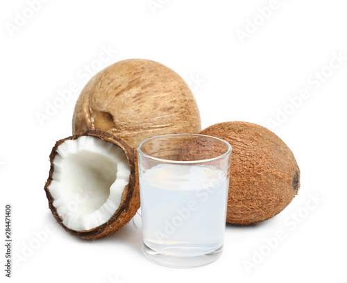 Glass of coconut milk and nuts on white background