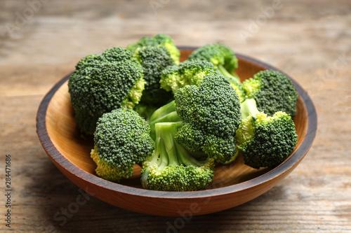 Wooden bowl of fresh broccoli on table, closeup