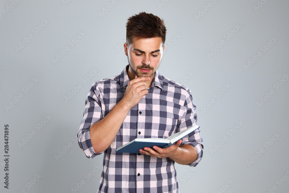 Handsome young man reading book on light background Handsome young man reading book on light background