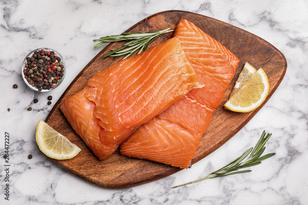 Wooden board with salmon fillet on marble table, flat lay Wooden board with salmon fillet on marble table, flat lay