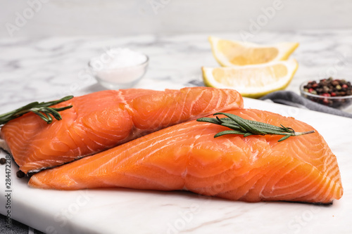 Marble board with tasty salmon fillet on table, closeup