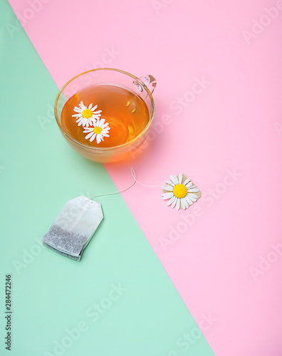 daisy flower, chamomile tea in cup and  tea bag. antidepression organic healthy beverage. creative minimalism concept. copy space. shallow depth photo