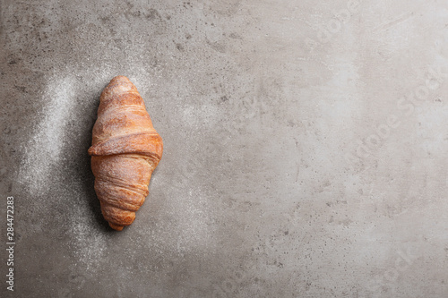 Tasty croissant with powdered sugar and space for text on grey background, top view. French pastry