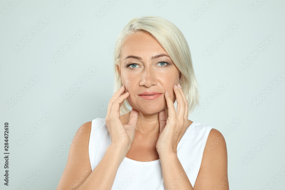 Portrait of mature woman with beautiful face on grey background Portrait of mature woman with beautiful face on grey background
