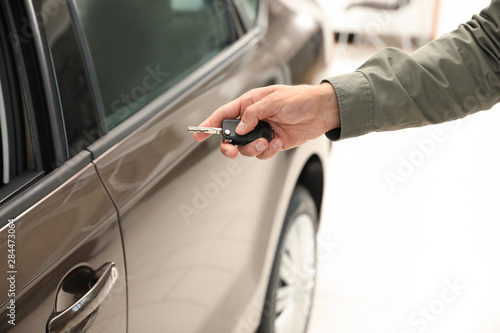 Young man checking alarm system with car key indoors, closeup