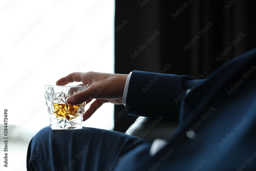 Obraz premium Young man with glass of whiskey indoors, closeup
