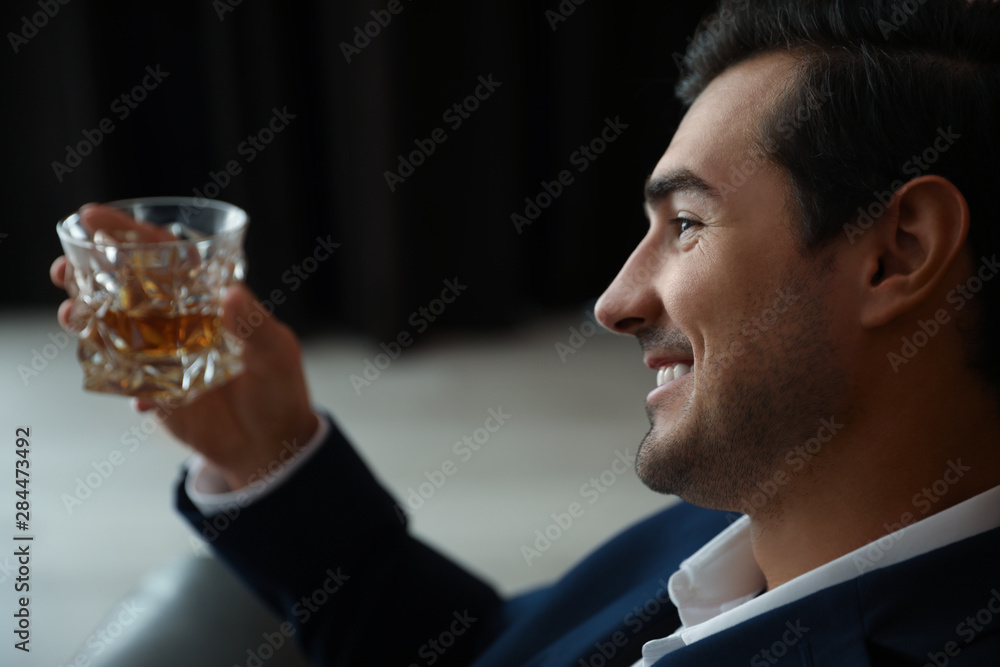 Young man with glass of whiskey indoors Young man with glass of whiskey indoors