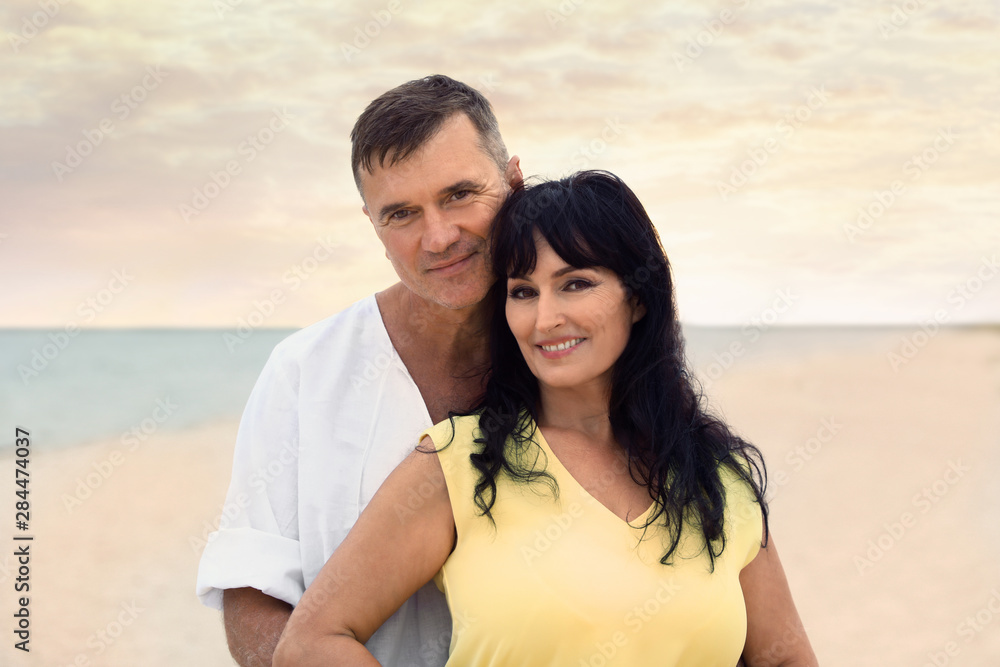 Happy mature couple spending time together on sea beach at sunset Happy mature couple spending time together on sea beach at sunset