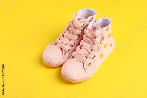 Pair of stylish child shoes on yellow background
