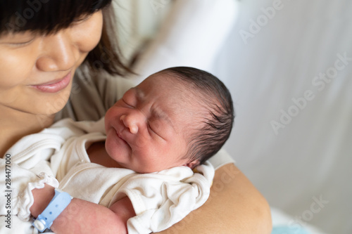 Asian mother looking her newborn baby.