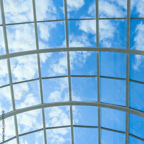abstract background with glass ceiling elements in a modern building. view of the blue sky through a glass window, separated by lattice elements.
