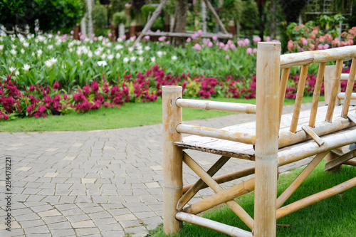 Fototapeta Naklejka Na Ścianę i Meble -  wooden bamboo bench in flower garden