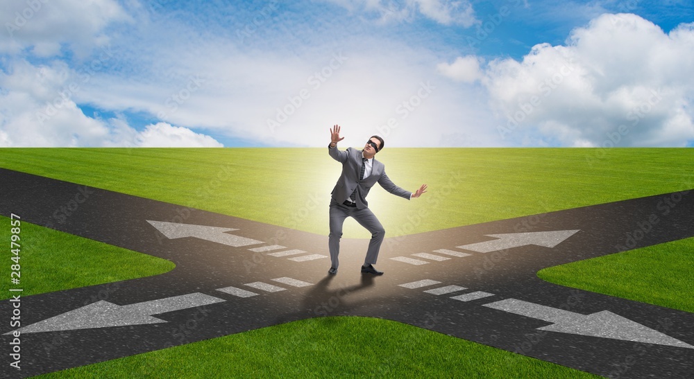Young businessman at crossroads in uncertainty concept Young businessman at crossroads in uncertainty concept