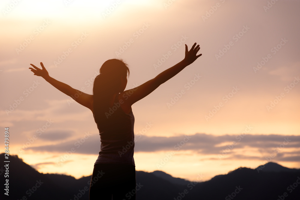 silhouette girl standing on mountain and rise up her hand