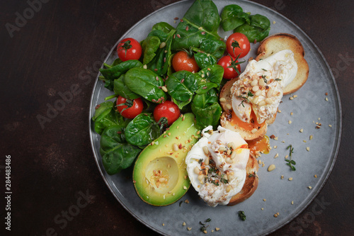 Toasts with avocado and poached egg, tomatoes and spinach, On a light gray background, Fresh morning breakfast