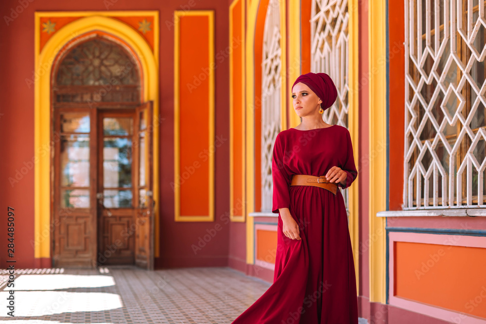 A portrait of a beautiful girl looks away and smiles beautifully against the background of the Stamboli cottage on 1.06.2019.