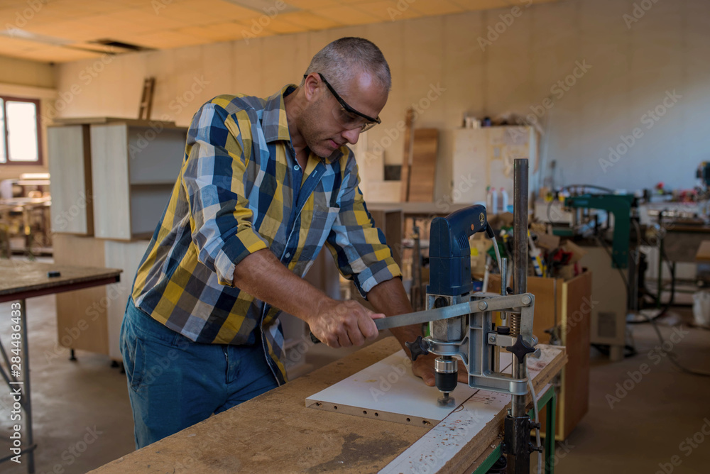 Carpenter Using Drilling Machine On Hardwood Board Carpenter Using Drilling Machine On Hardwood Board