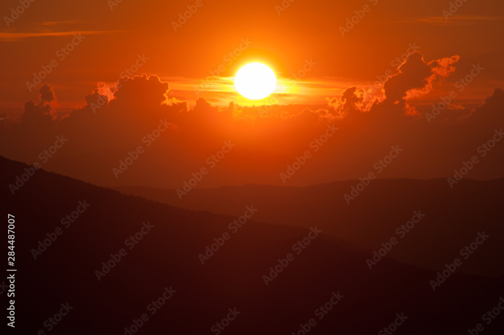 Epic sunset landscape with vibrant orange sky and hills