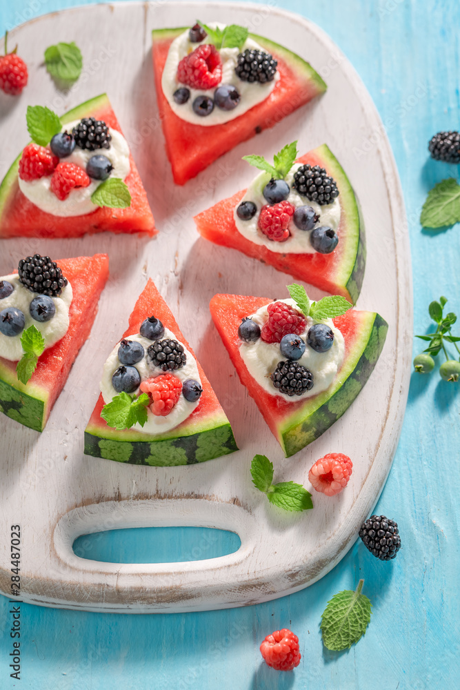 Top view of watermelon pizza with blueberries, raspberries and cream