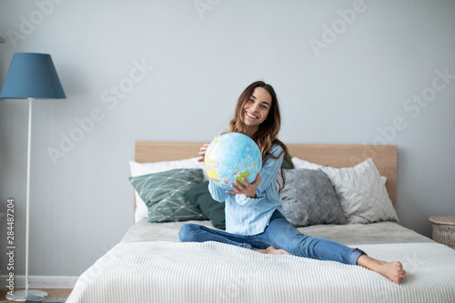 Happy woman holding a globe, indoor.
