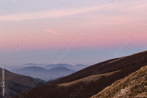 Beautifully colored sky at dusk, with mountains layers and mist between them
