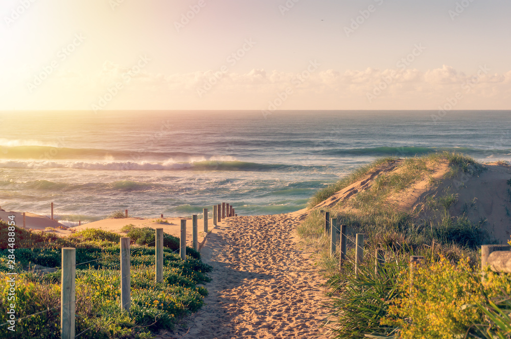 Entrance to the beach with beautiful waves at sunrise