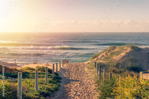 Fototapeta Naklejka Na Ścianę i Meble -  Entrance to the beach with beautiful waves at sunrise