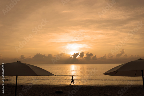 Sunset on the sea. Silhouette of people walking in sunshine along the beach at sunset.