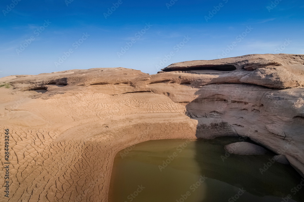 Fototapeta premium view of Nature rock and water in Mekong river with blue sky background, Sam Phan Bok known as The Grand Canyon of Thailand, attraction in Ubon Ratchathani, Thailand.