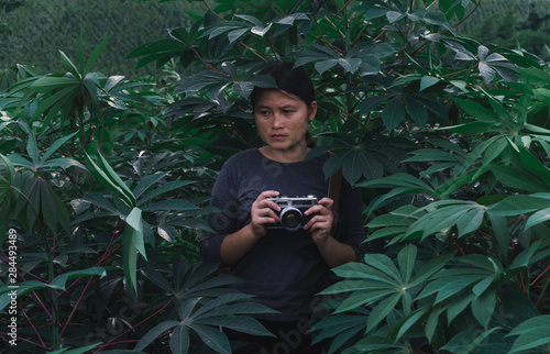Young women travel on cassava fields, hold old cameras, take pictures.